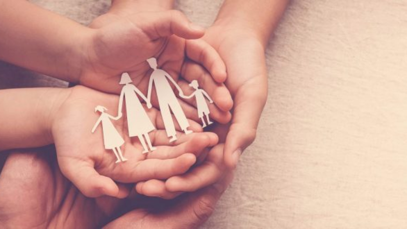 Adult and children hands holding paper family cutout, family home, foster care, homeless support concept